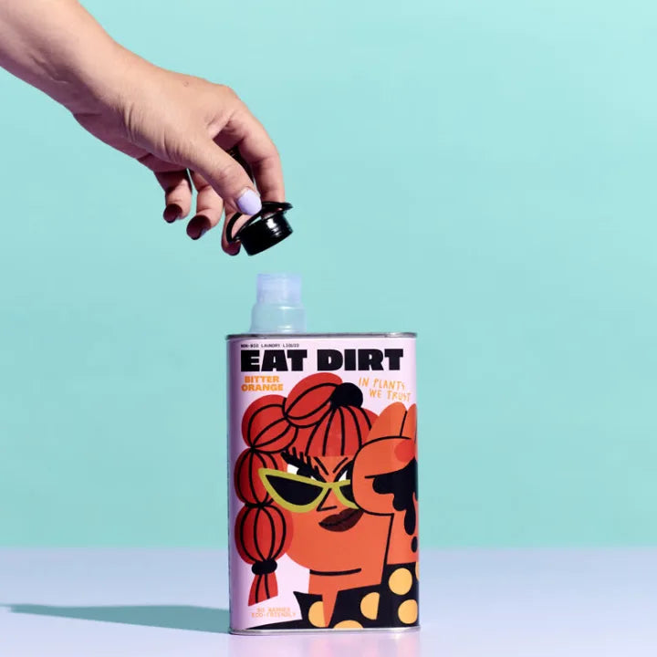 A hand lifting the cap off an EAT DIRT tin