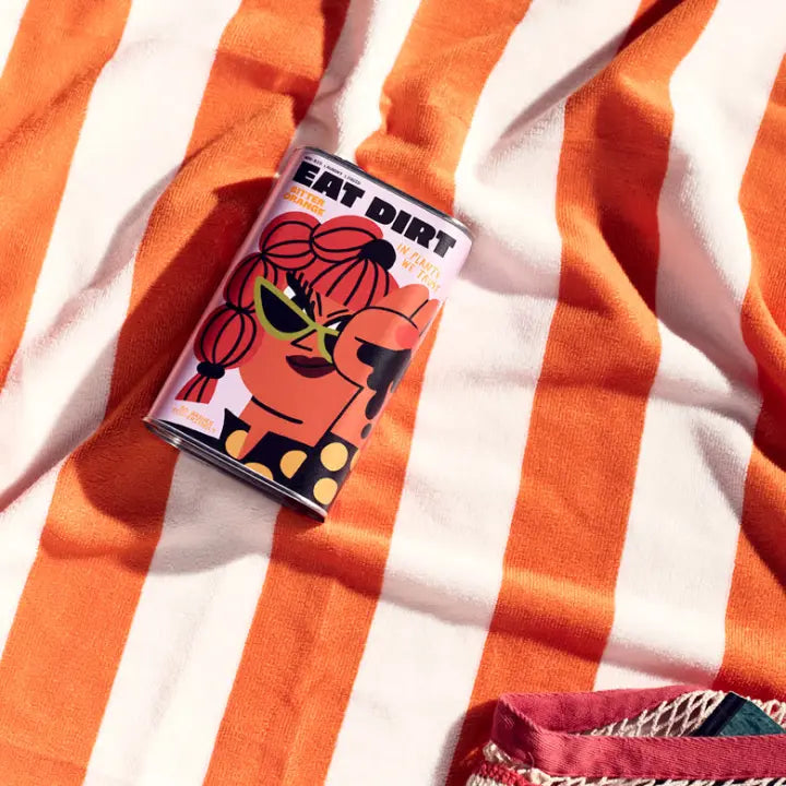 An EAT DIRT tin resting on an orange striped towel