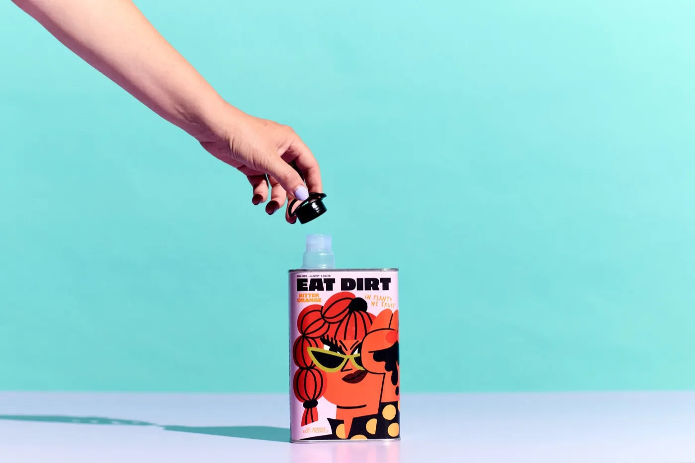 Hand opening an Eat Dirt tin